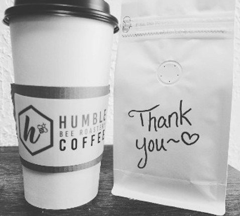 take out cup of coffee with a bag next to it