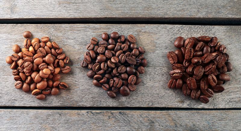 Three piles of coffee beans, each roasted to a different level